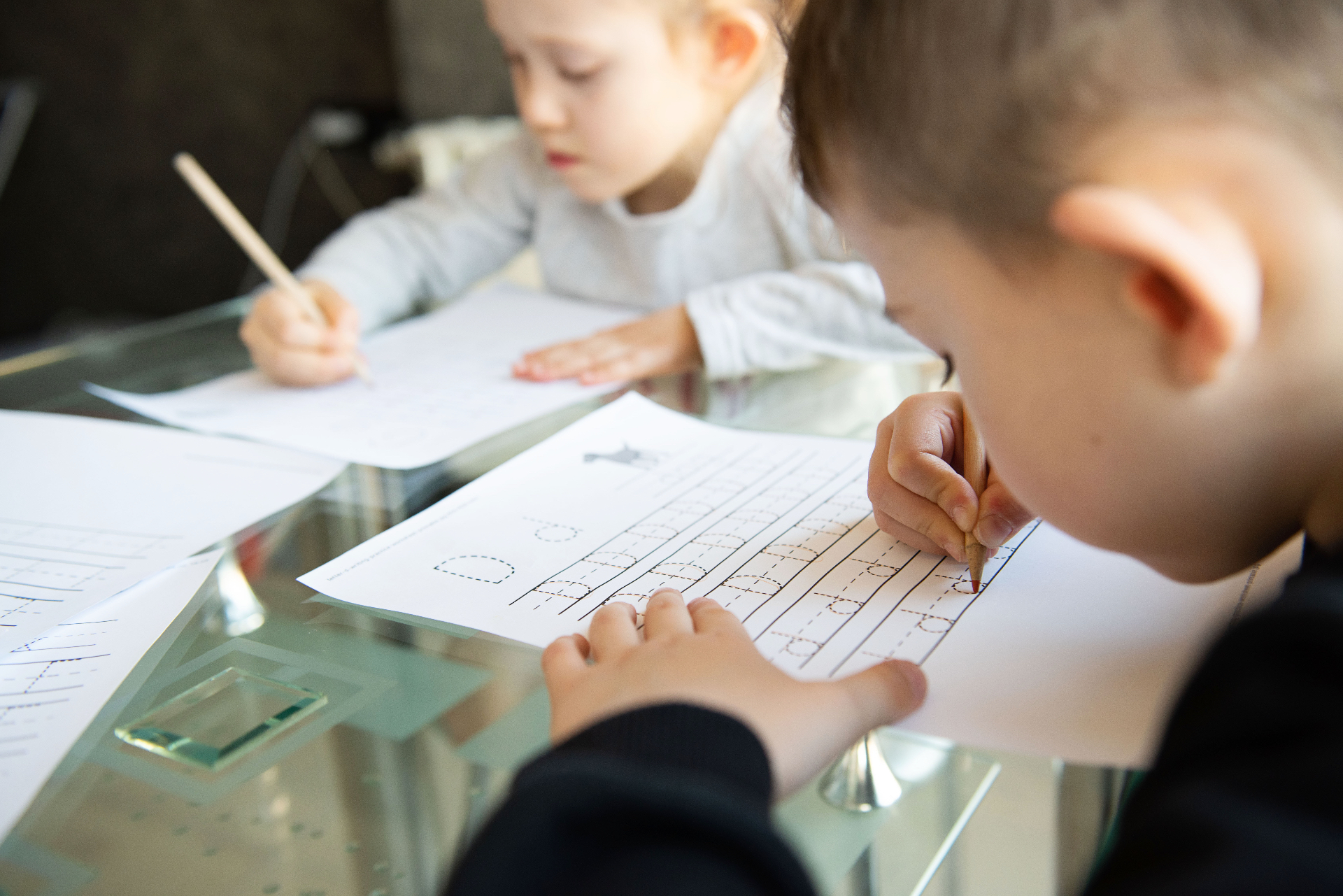 Children practicing letter tracing at a desk